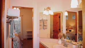A bathroom with a sink, mirror, towel rack, and a wooden door. - Rio Oasis with Southwest charm (Albuquerque)