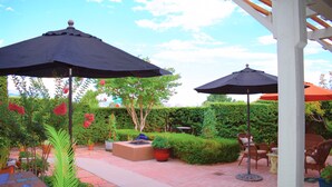 An outdoor patio with two umbrellas, potted plants, and outdoor furniture. - Rio Oasis with Southwest charm (Albuquerque)