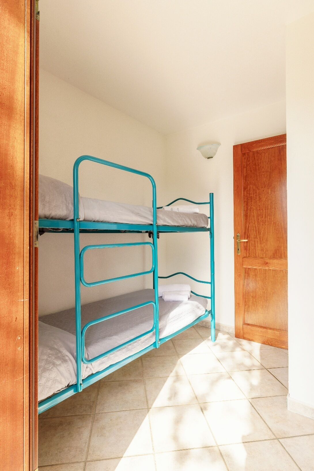 Una habitación con tres literas, una puerta de madera y una lámpara en la pared.
