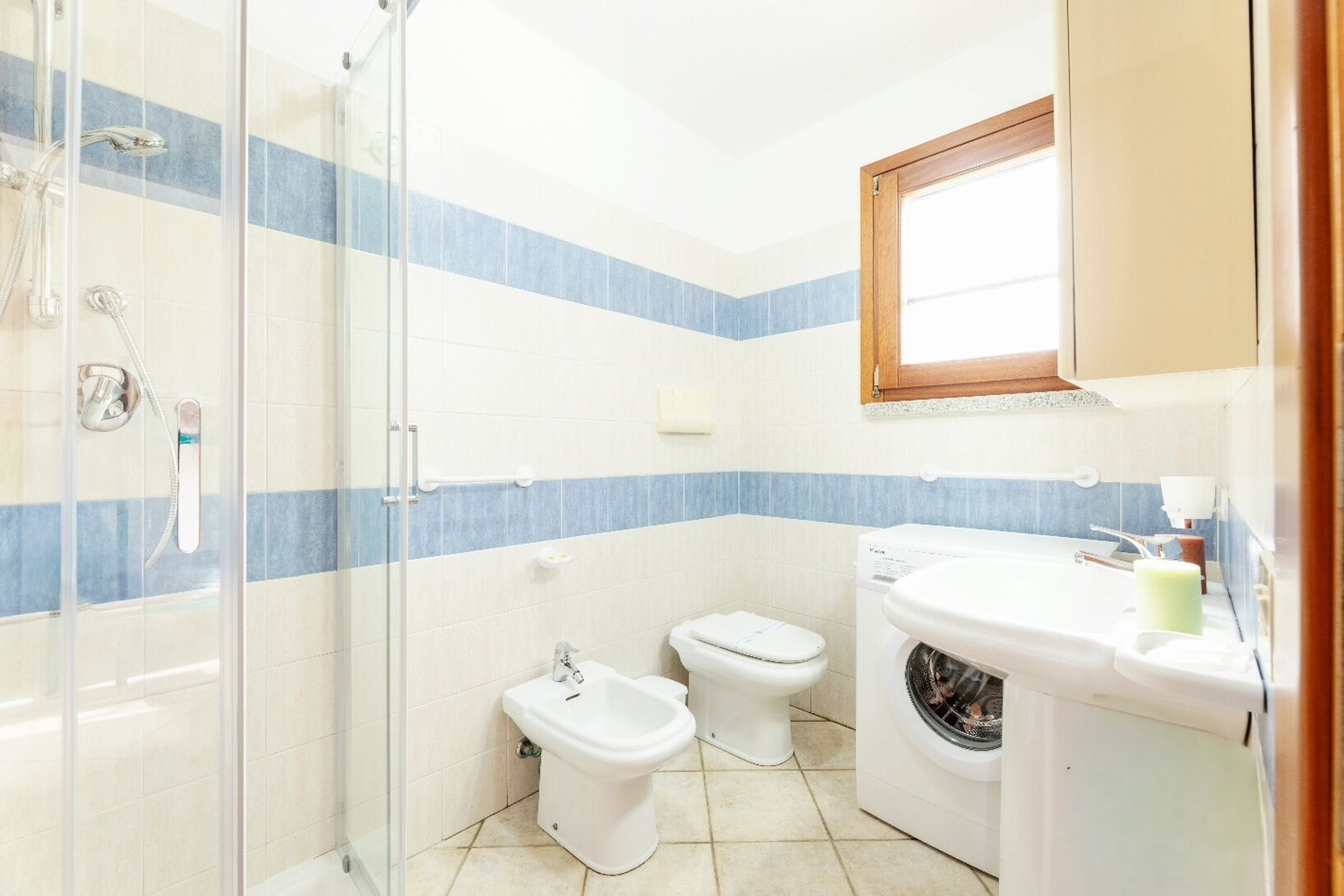 Un baño con cabina de ducha de vidrio, un bidé, un inodoro y una lavadora.