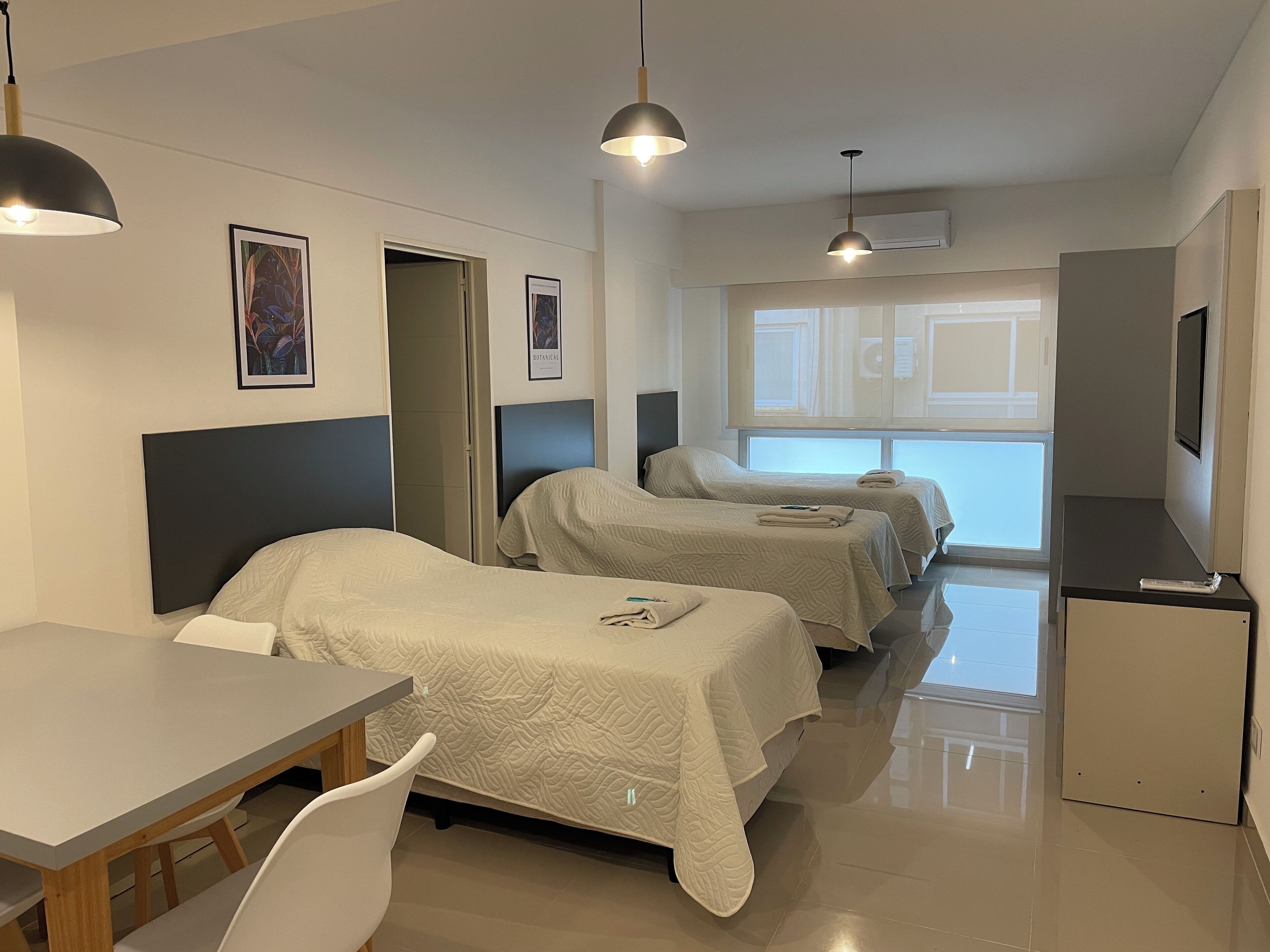 A hotel room with two beds, a desk, and a TV.