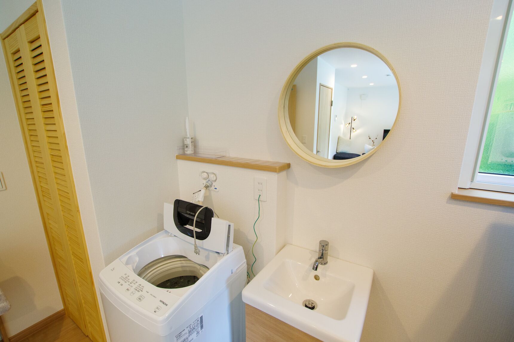 Une petite salle de bain équipée d’un lave-linge à chargement frontal, d’un lavabo et d’un miroir.