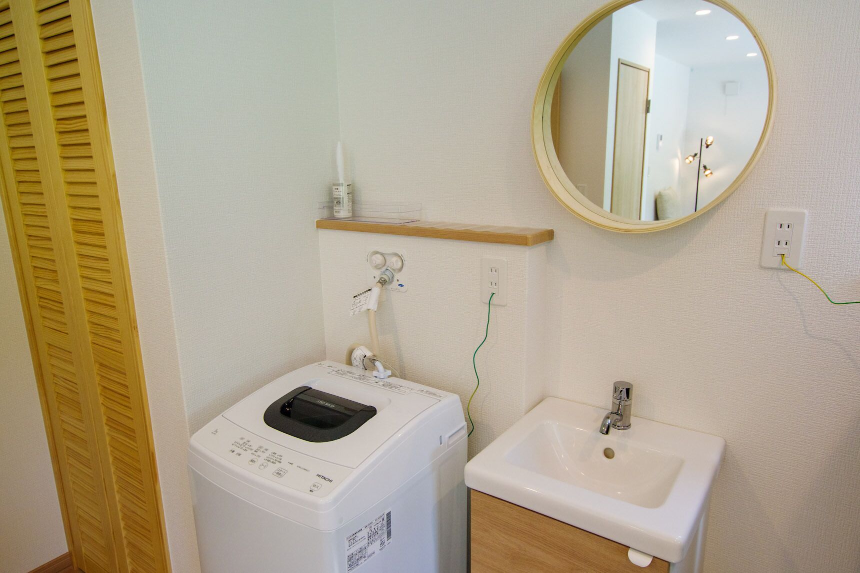 Une petite salle de bain équipée d’un lave-linge, d’un évier et d’un miroir.
