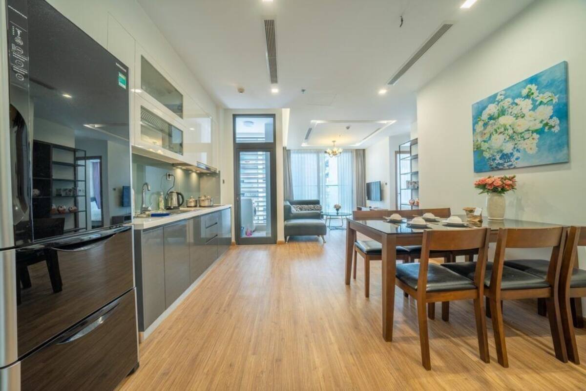 A modern kitchen with stainless steel appliances, a dining area with wooden furniture, and a large window providing natural light.