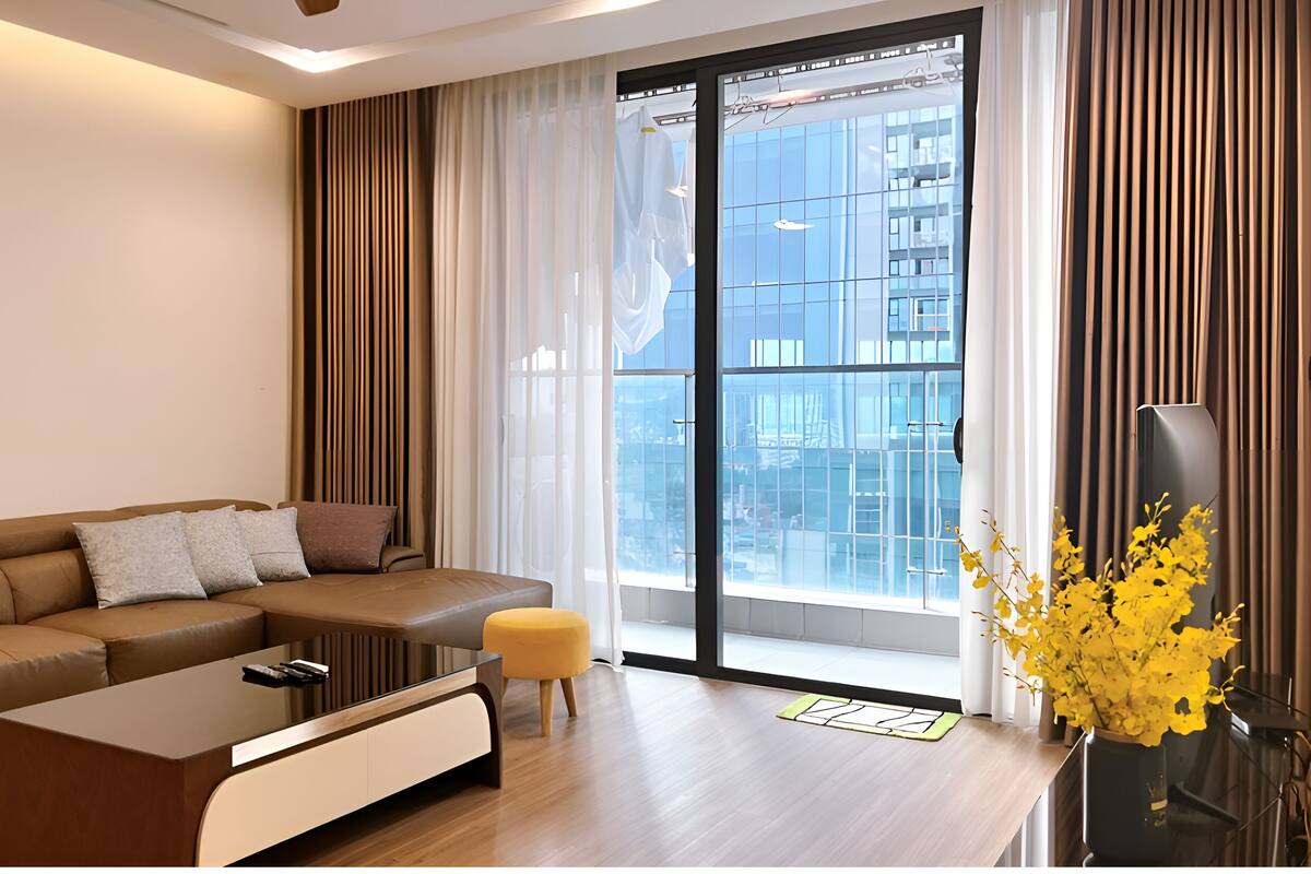 A modern living room with a sectional sofa, a coffee table, and a large window with curtains.