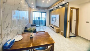 Een moderne hotelkamer met een marmeren wand, een houten eettafel, een televisie en een balkon met uitzicht.