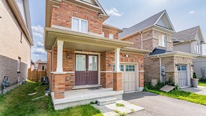 A two-story brick house with a front porch, a garage, and a well-maintained lawn. - Newly renovated cozy studio (Woodstock)