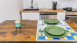 A kitchen with a wooden table set for two, a candle, and a colorful tablecloth. - Newly renovated cozy studio (Woodstock)