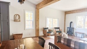 A spacious living room with a wooden table, chairs, a sofa, and a fireplace.