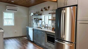 A modern kitchen with wooden beams, stainless steel appliances, and a large window.