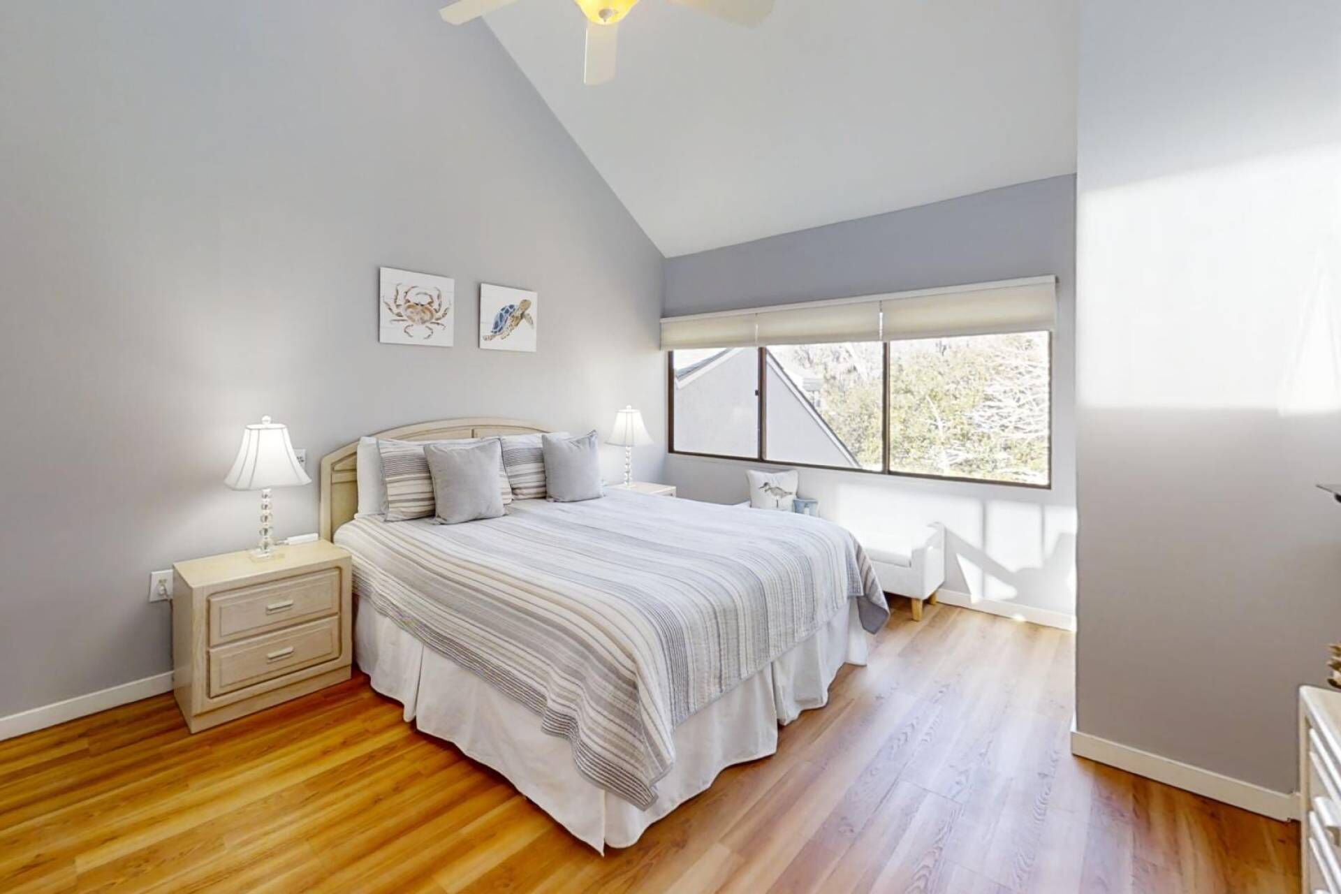 Quarto com cama, mesas de cabeceira, janela e obras de arte na parede.