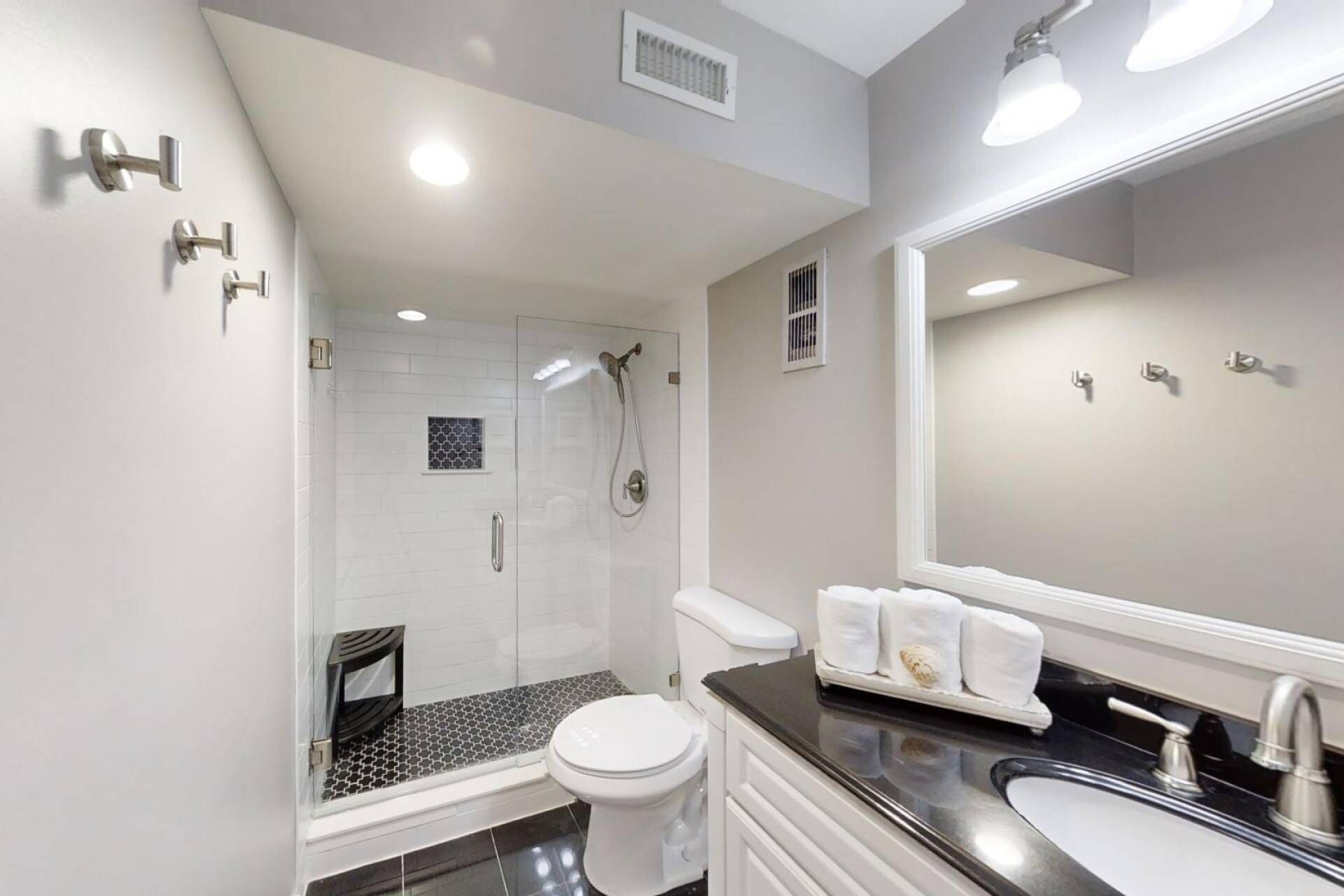 A modern bathroom with a glass-enclosed shower, a toilet, and a sink with a black countertop.
