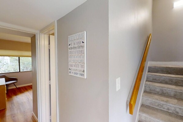 A staircase with a wooden handrail and a wall with a motivational poster. - Treetops 4502 - an iTrip Hilton Head Home (Hilton Head Island)