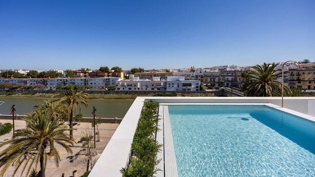 A clear blue pool with a view of a coastal town and a body of water.