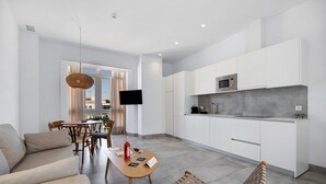 Una cocina moderna con armarios blancos, un microondas integrado y un comedor con mesa y sillas.