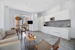 A modern kitchen with white cabinets, a built-in microwave, and a dining area with a table and chairs. - Apartment 'Gran Suite Balcón 4' with Balcony, Wi-Fi and Air Conditioning (CHICLANA DE LA FRONTERA)