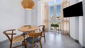 Un comedor moderno con una mesa redonda, sillas de madera, una lámpara colgante de mimbre y un televisor montado en la pared.