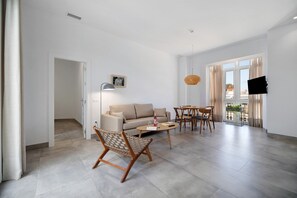 Un salon moderne avec un canapé, une table basse et un fauteuil en osier.