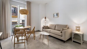 A modern living room with a sofa, a round table with chairs, a hanging light fixture, and a small side table with a lamp. - Apartment 'Balcón Luxury 2' with Balcony, Wi-Fi and Air Conditioning (CHICLANA DE LA FRONTERA)