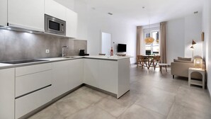 A modern kitchen with a built-in microwave, a dining area with a table and chairs, and a living space with a sofa and lamp. - Apartment 'Balcón Luxury 2' with Balcony, Wi-Fi and Air Conditioning (CHICLANA DE LA FRONTERA)