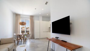 Una sala de estar moderna con un sofá, una mesa de centro, un comedor y un televisor montado en la pared.