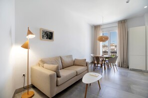 Un salon moderne comprenant un canapé, une petite table, un lampadaire et un coin repas avec des chaises et une table.