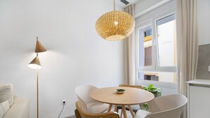 Une pièce moderne avec une table ronde en bois, des chaises blanches, un lampadaire et un luminaire suspendu.