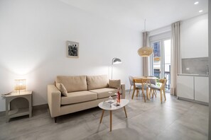 Una sala de estar moderna con sofá, mesa de centro, lámpara y comedor.