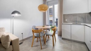 Uma cozinha moderna com uma mesa redonda, duas cadeiras, um lustre e vista para o exterior.