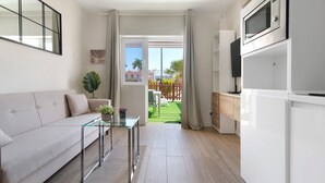 Un salon moderne avec un canapé, une table basse en verre et une vue sur un jardin, accessible par une porte coulissante.
