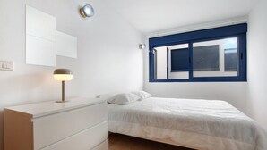 Un dormitorio con cama, cómoda, espejo y ventana con persianas.