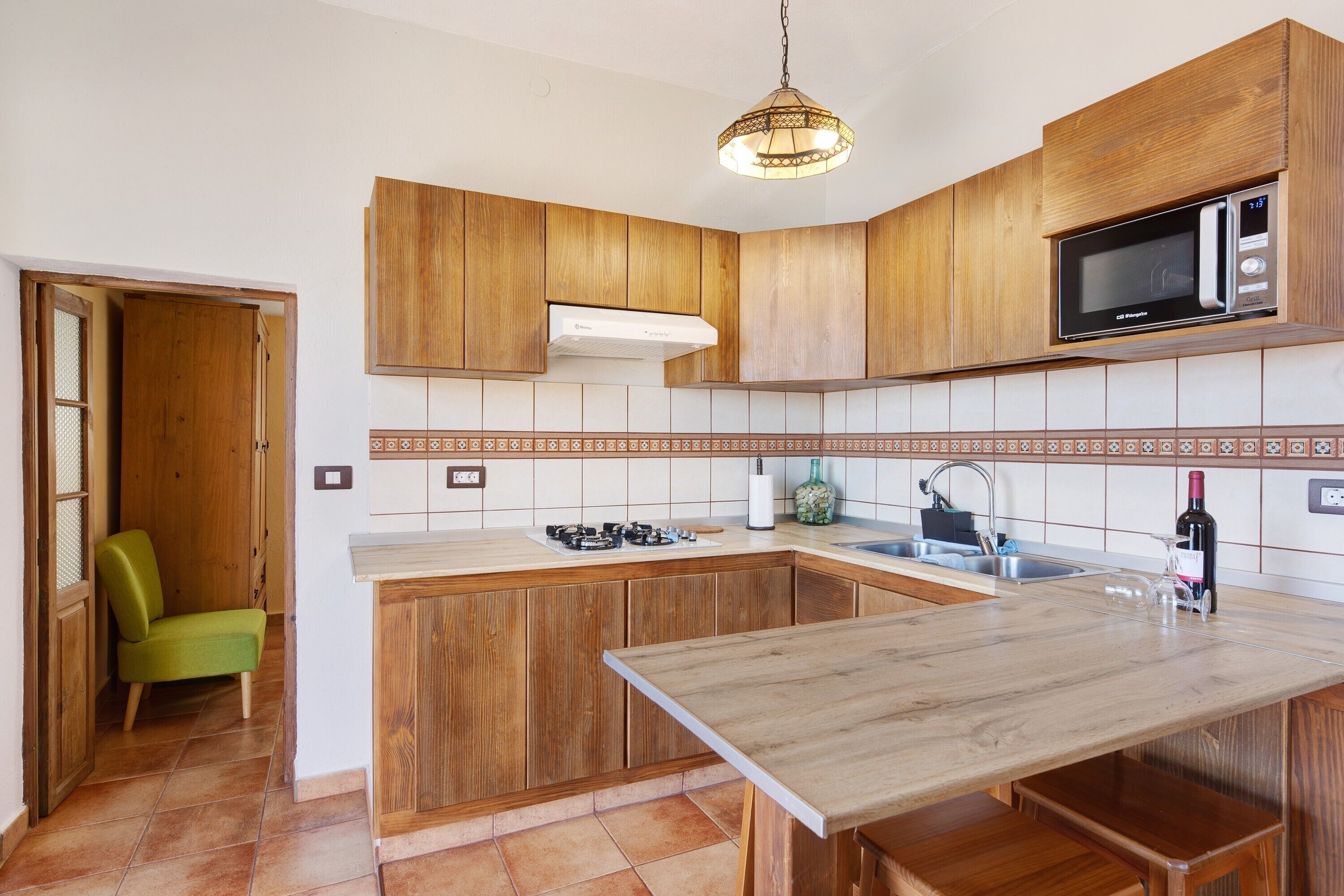 A kitchen with wooden cabinets, a microwave, a sink, and a dining area.