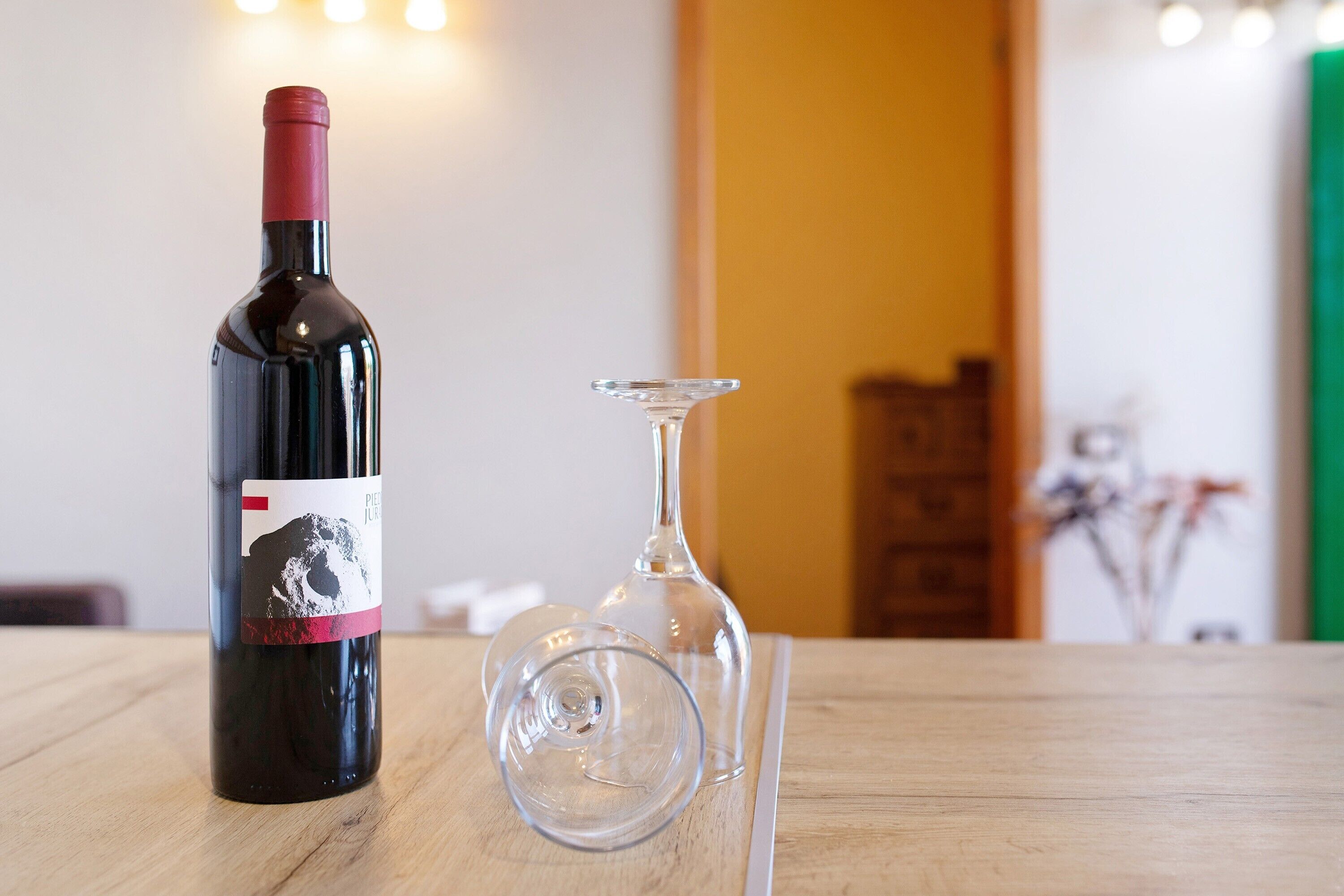 Una botella de vino y una copa vacía sobre una mesa de madera.