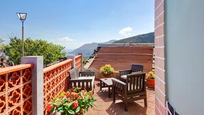 Una terraza con una mesa y sillas, una planta en maceta y vistas a las montañas.
