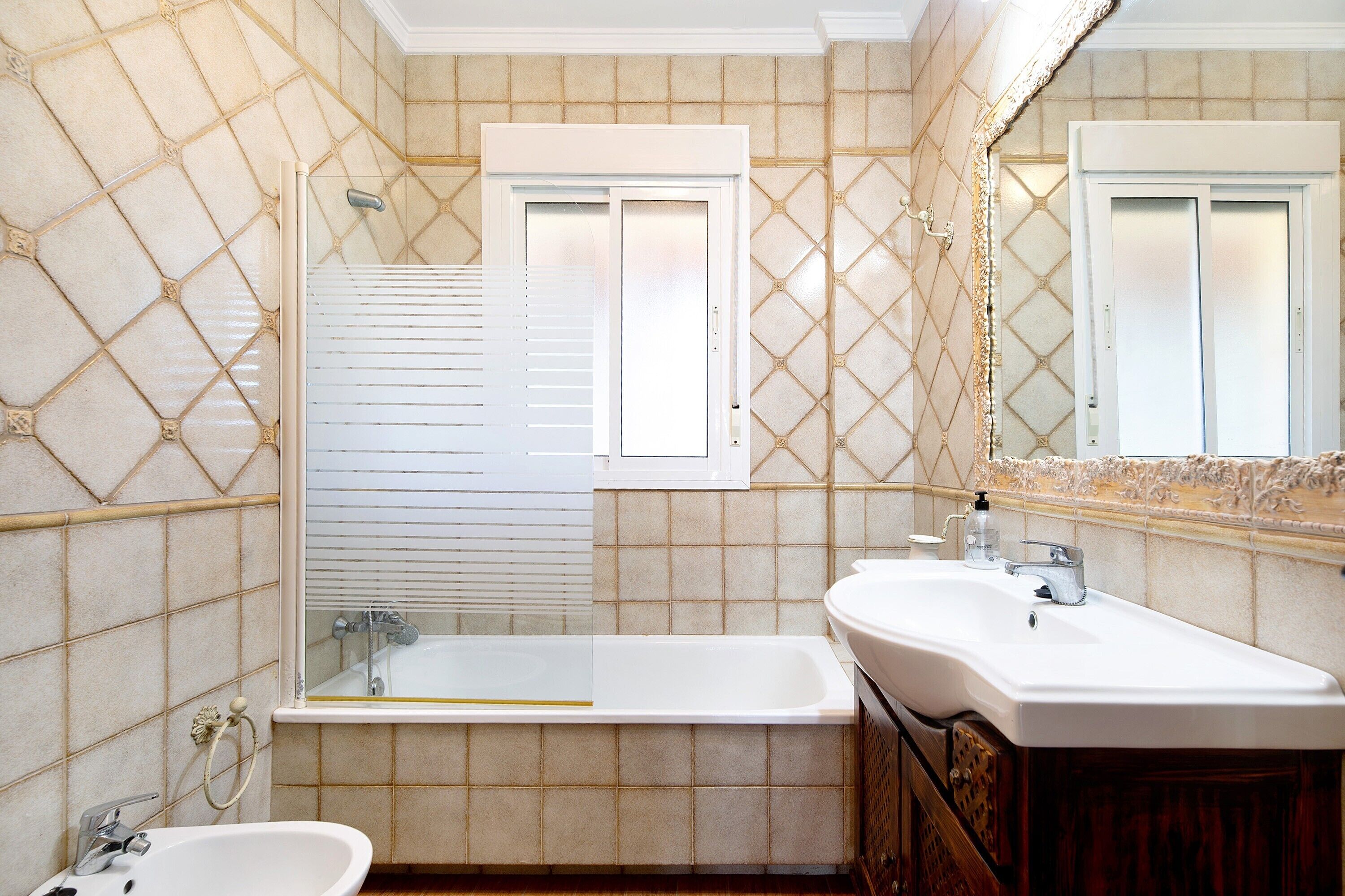 Un baño con bañera, lavamanos y espejo.