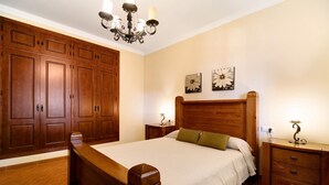 Een slaapkamer met een houten bed, nachtkastjes, een kaptafel en een kroonluchter.