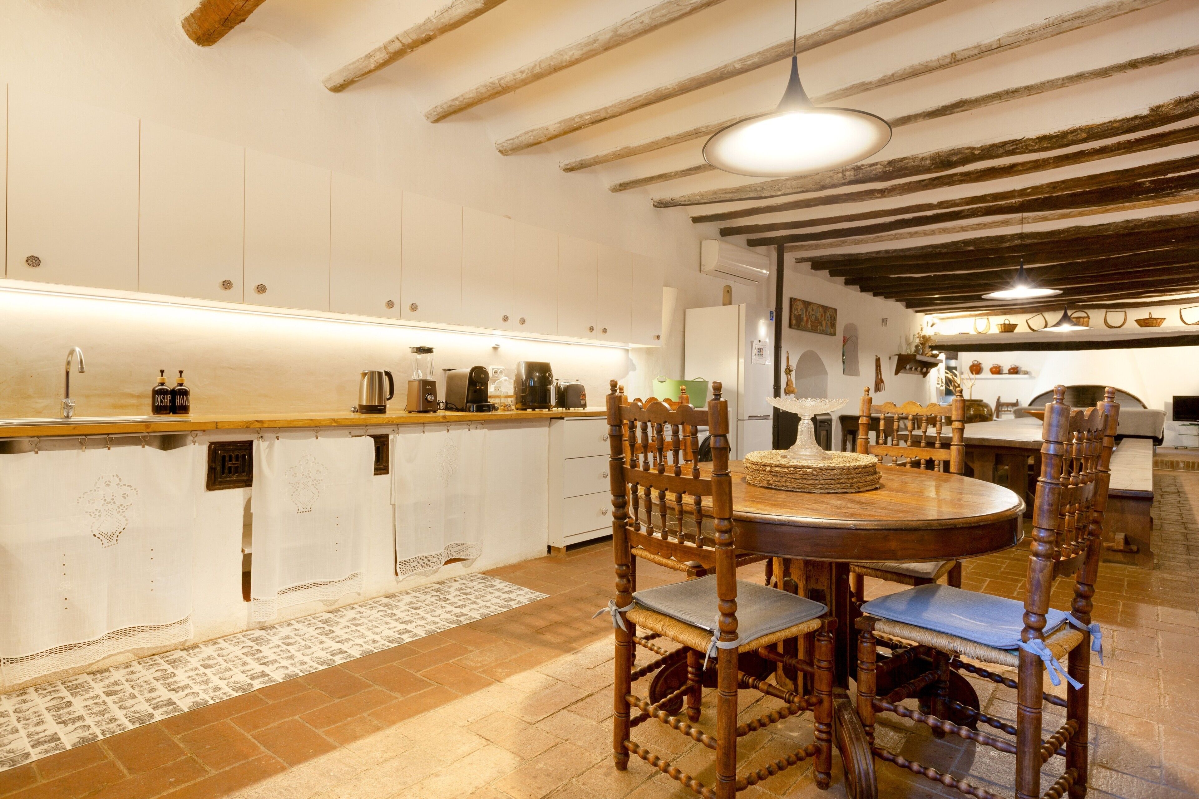 Una cocina rústica con vigas de madera, una mesa redonda de madera y una isla integrada con un lavamanos.