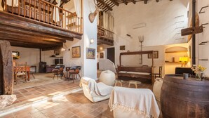 A rustic interior with a wooden balcony, a large barrel, and a cozy seating area.