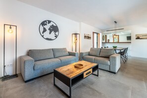 A modern living room with two grey sofas, a wooden coffee table, and a world map on the wall.