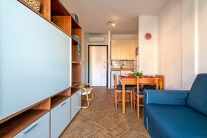 A compact living space with a kitchenette, dining area, and a sofa. - Apartment 'Gio's' with Shared Pool, Private Garden and Air Conditioning (Lu Bagnu)