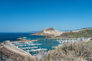 A coastal marina with boats, a fortified hilltop, and a town below. - Apartment 'Gio's' with Shared Pool, Private Garden and Air Conditioning (Lu Bagnu)