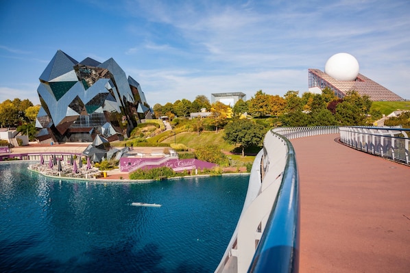 Un bâtiment moderne doté d’une conception géométrique originale, situé au bord de l’eau et comprenant une grande structure sphérique.
