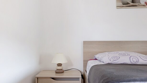 Un lit avec un oreiller à motifs, une table de chevet avec une lampe et un tableau accroché au mur.