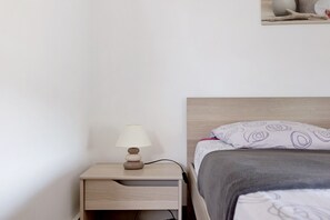 Un lit avec un oreiller à motifs, une table de chevet avec une lampe et un tableau accroché au mur.