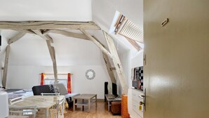 Une pièce de style « loft », avec des poutres en bois apparentes, une table à manger avec des chaises, un canapé, une petite table et un miroir au mur.