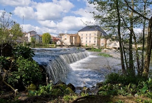 Une cascade, une rivière et des bâtiments en arrière-plan.
