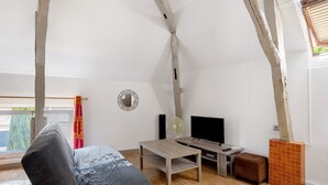 Una habitación con cama, televisión, mesa y ventana.