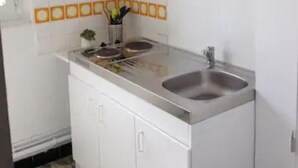 Una cocina con armarios blancos, dos fregaderos y un salpicadero azulejado.