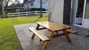 Una mesa de picnic de madera con bancos en un espacio al aire libre empedrado.