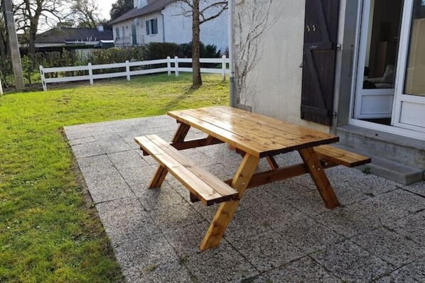 Ein hölzernes Picknicktisch mit Bänken in einem gepflasterten Außenbereich.